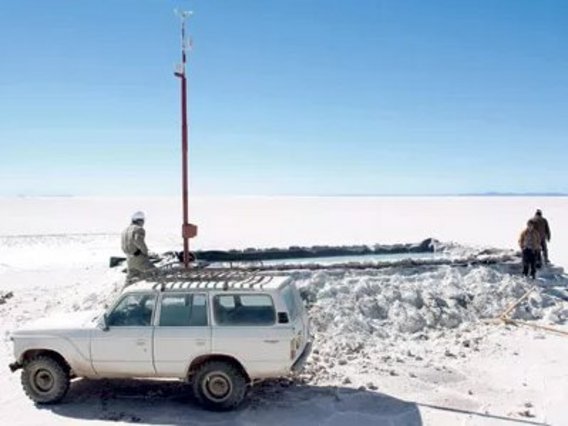 Deserto de Salar de Uyuni - Bolívia. Um jipe estacionado em uma bacia de sal. Há três pessoas ao redor da piscina.