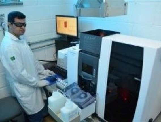 Um técnico fica em frente a um dispositivo e realiza análises da água.