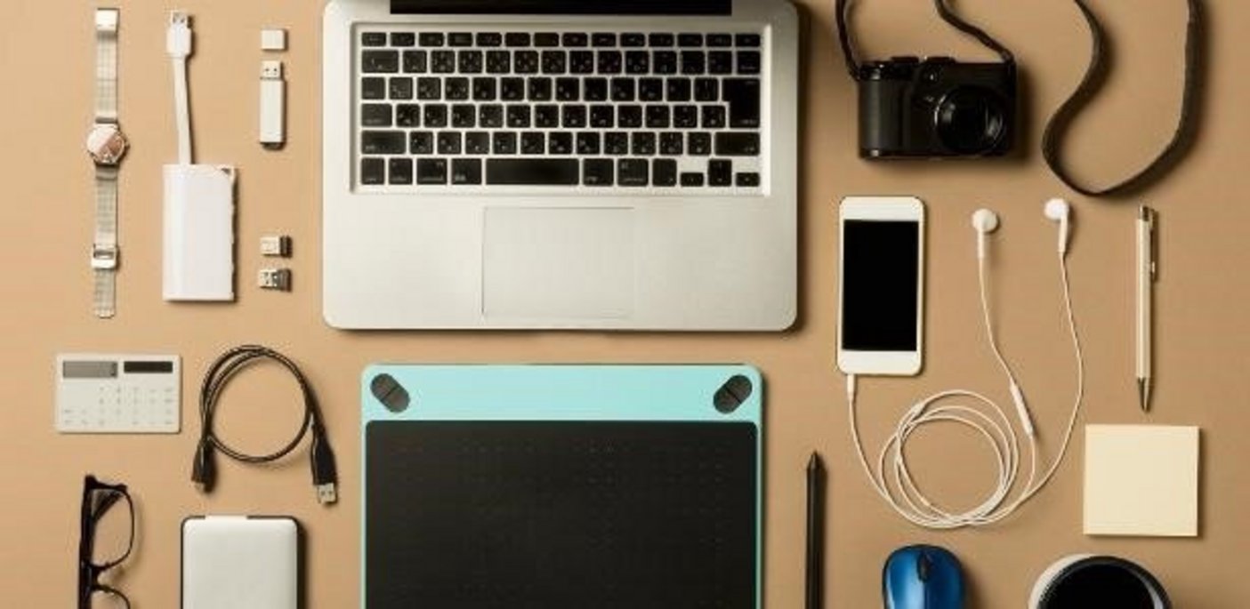 Dispositivos eletrônicos em uma mesa que contêm terras raras em sua composição: por exemplo, laptop, telefone celular, câmera, relógio, óculos, cabo de carregamento, mouse, tablet
