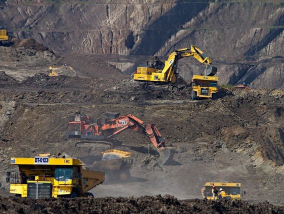 Mineração a céu aberto - escavadeiras carregam terra e rocha em caminhões