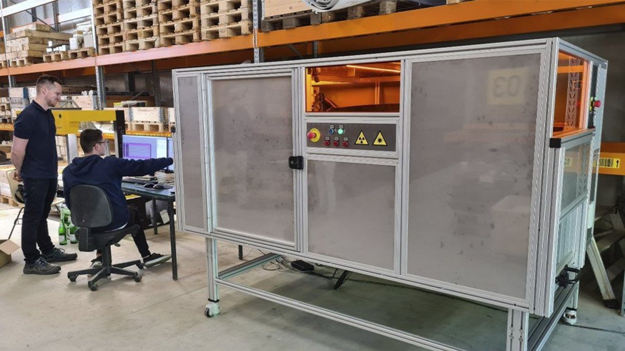 Ancorelog instalada em um depósito. Um homem senta-se ao lado dele em uma cadeira e mostra a um segundo homem algo no computador.