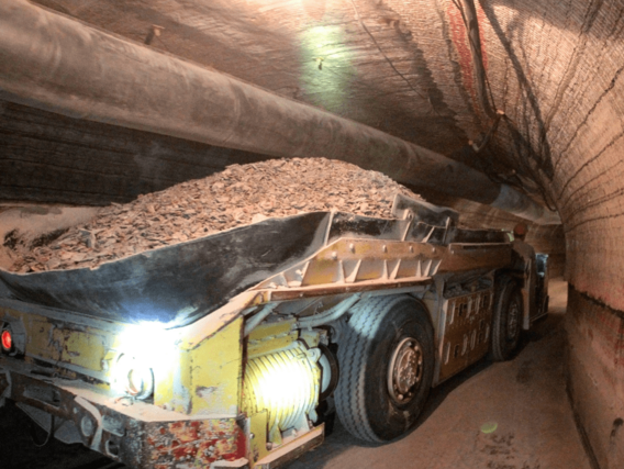 Um caminhão carregado de rocha passa por um túnel