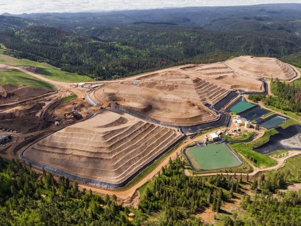 Paisagem de mineração a céu aberto cercada pela natureza.