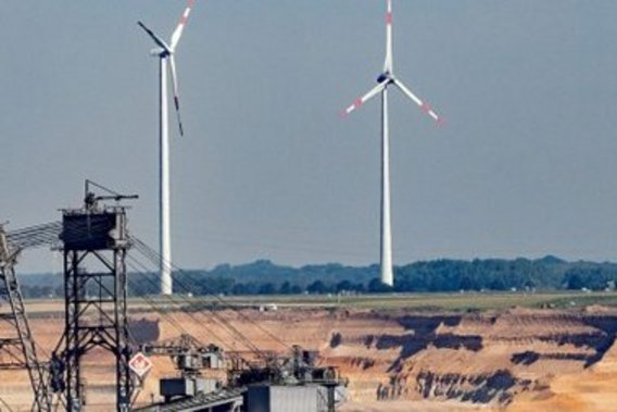 Uma mina a céu aberto com duas turbinas eólicas ao fundo.