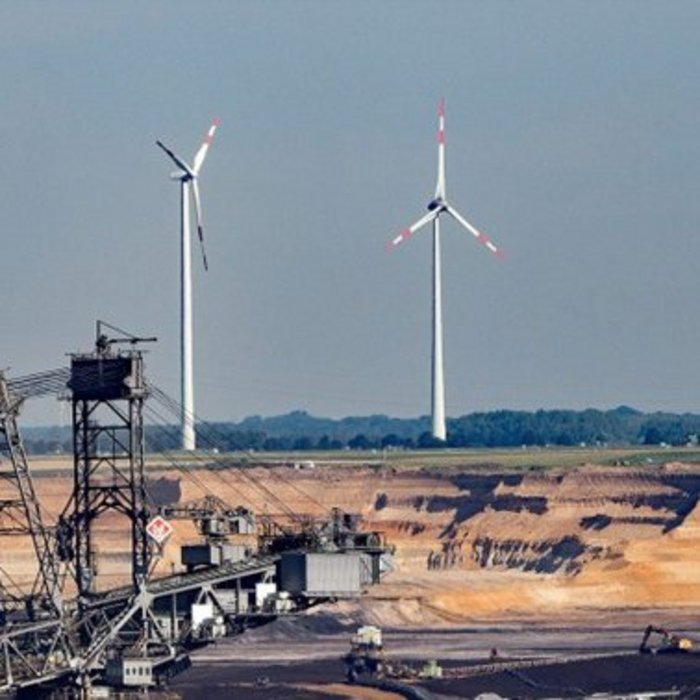 Uma mina a céu aberto com duas turbinas eólicas ao fundo.